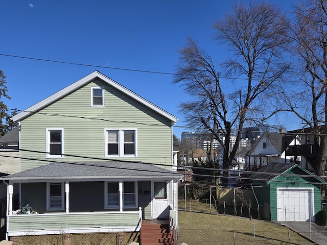 view of property exterior with an outbuilding, a porch, a yard, and roof with shingles