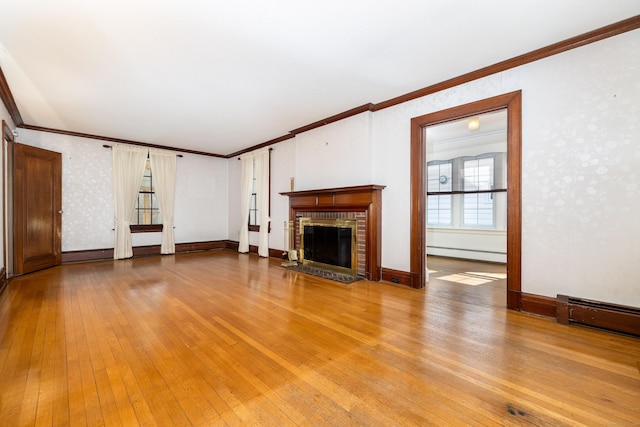 unfurnished living room featuring light wood-style flooring, a fireplace, wallpapered walls, and a baseboard heating unit