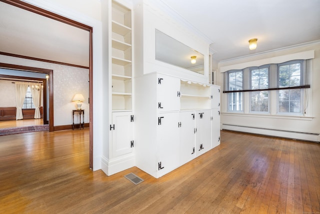 interior space with hardwood / wood-style floors, visible vents, baseboard heating, and ornamental molding