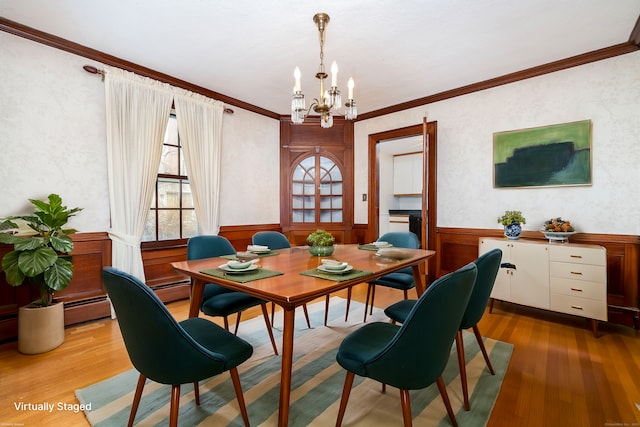 dining area featuring a notable chandelier, wainscoting, crown molding, and wood finished floors