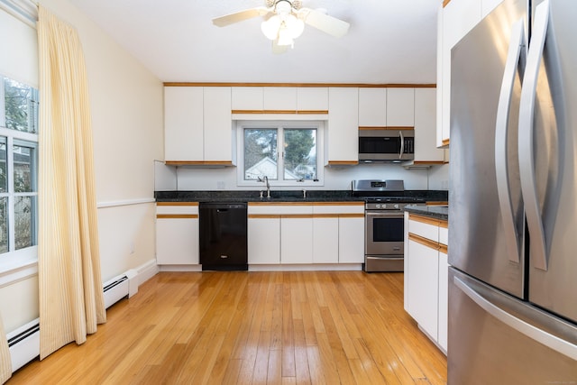 kitchen with a sink, white cabinetry, stainless steel appliances, light wood finished floors, and baseboard heating