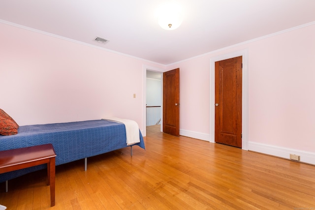 bedroom featuring visible vents, crown molding, light wood-type flooring, and baseboards