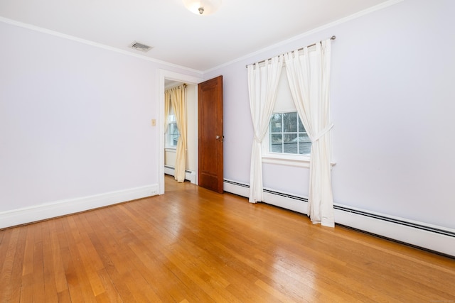 spare room featuring light wood finished floors, visible vents, baseboards, ornamental molding, and baseboard heating