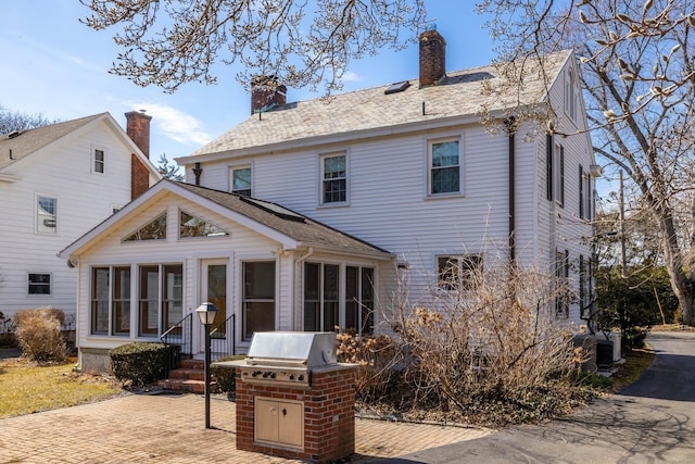 rear view of house featuring a chimney and a sunroom