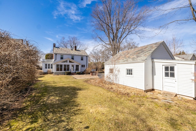 back of house with an outbuilding and a lawn