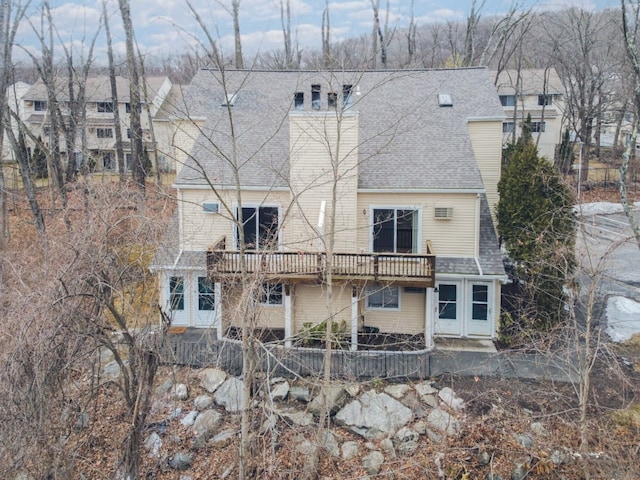 rear view of property with a shingled roof and a chimney