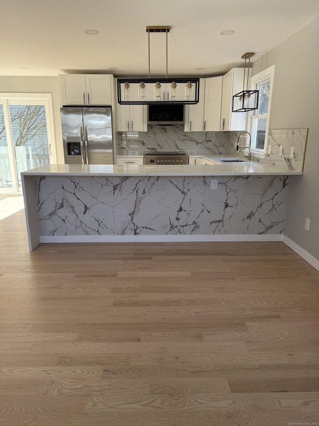 kitchen featuring light wood finished floors, white cabinetry, stainless steel appliances, and a sink