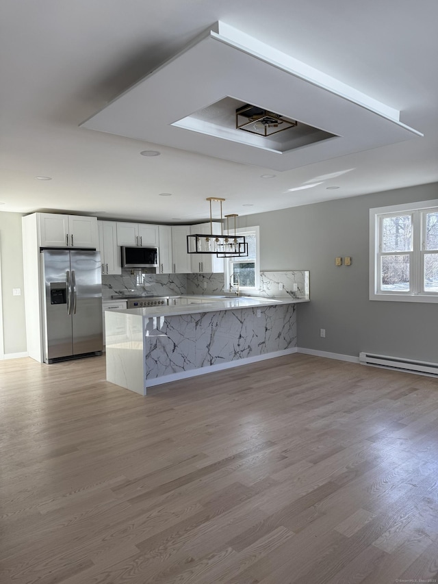 kitchen with a peninsula, light wood-style flooring, white cabinets, and stainless steel appliances