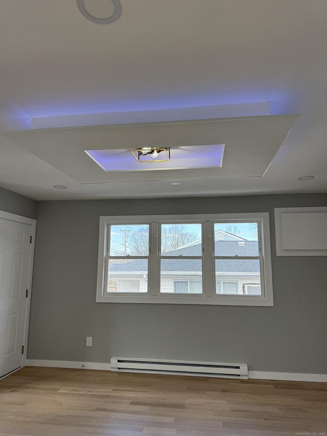 spare room with light wood-type flooring, baseboards, and a baseboard heating unit