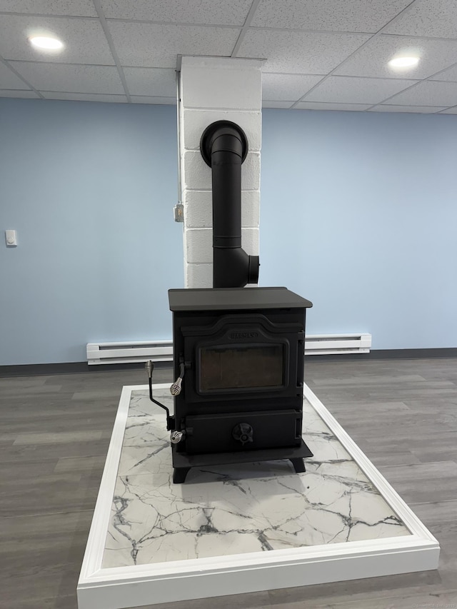 interior details with a baseboard radiator, a wood stove, baseboards, and wood finished floors