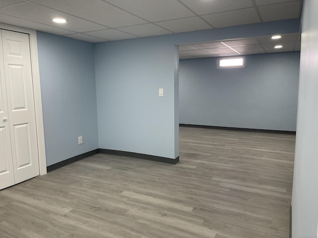 below grade area featuring a paneled ceiling, baseboards, wood finished floors, and recessed lighting