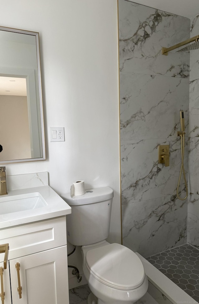 bathroom with marble finish floor, toilet, vanity, and a marble finish shower