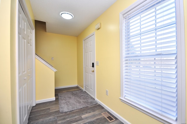 entryway with baseboards, visible vents, and dark wood finished floors