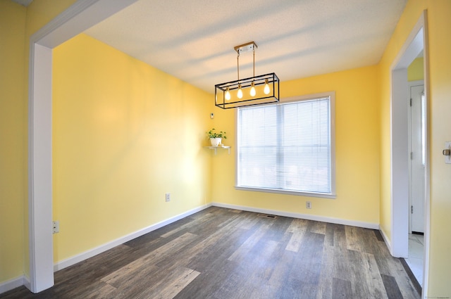 unfurnished dining area featuring visible vents, baseboards, dark wood finished floors, and a textured ceiling