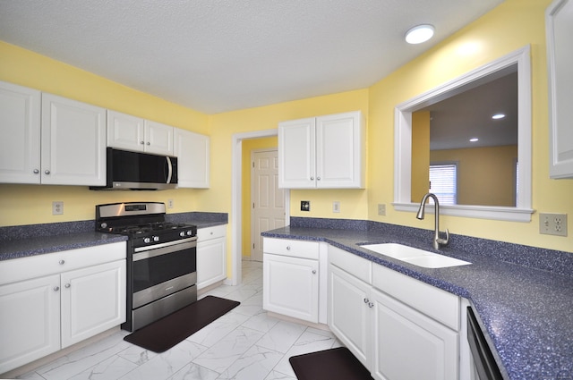 kitchen with marble finish floor, stainless steel appliances, a sink, and white cabinetry