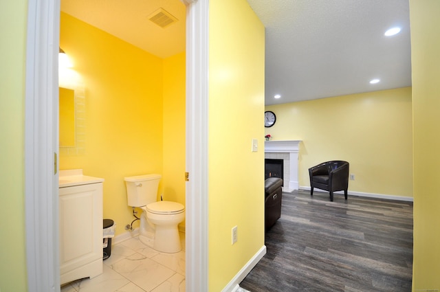 bathroom featuring baseboards, visible vents, toilet, a fireplace, and recessed lighting