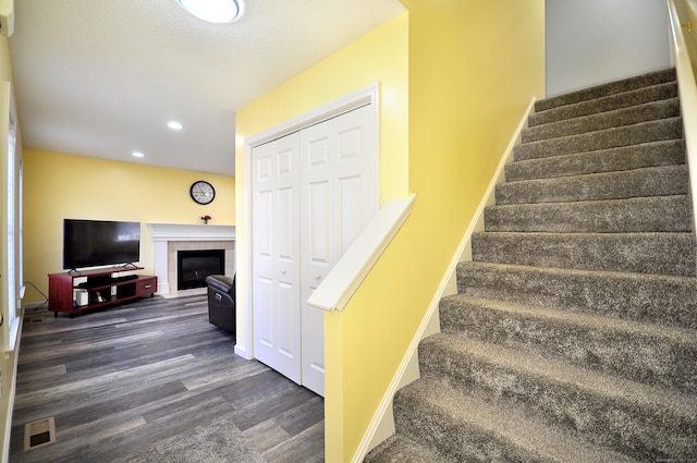 stairs with a fireplace, recessed lighting, visible vents, wood finished floors, and baseboards