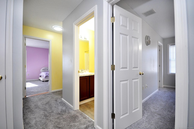 hallway with light carpet, baseboards, and visible vents