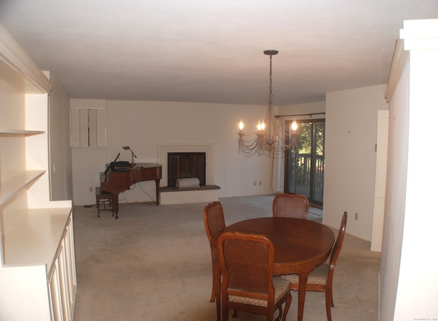 dining area with a glass covered fireplace, light colored carpet, and an inviting chandelier