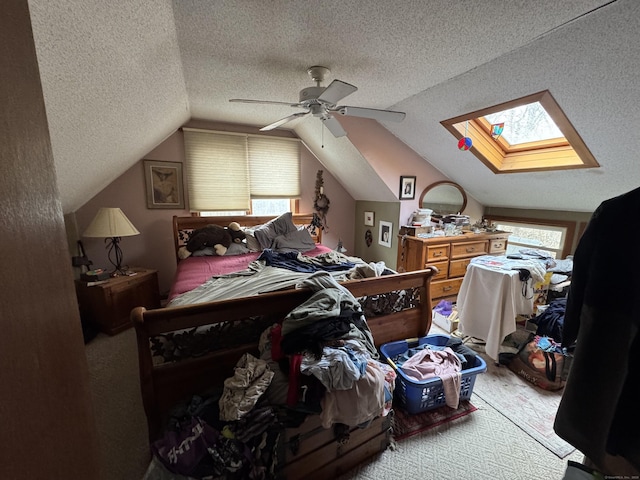 bedroom featuring lofted ceiling with skylight, ceiling fan, and a textured ceiling