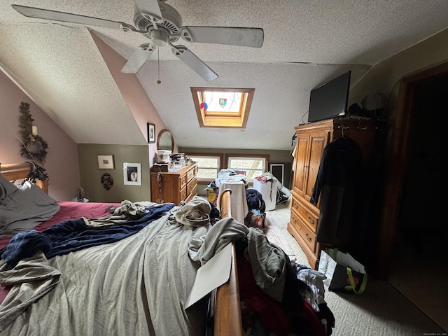 bedroom with a ceiling fan, vaulted ceiling with skylight, and a textured ceiling