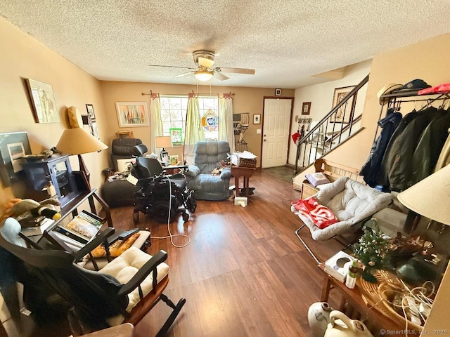 living area with a textured ceiling, stairs, a ceiling fan, and wood finished floors