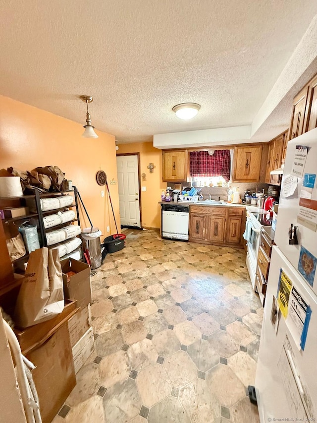 kitchen with light floors, light countertops, hanging light fixtures, brown cabinetry, and white appliances