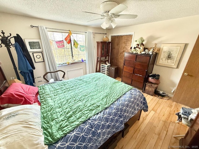 bedroom with a textured ceiling, a ceiling fan, and hardwood / wood-style floors