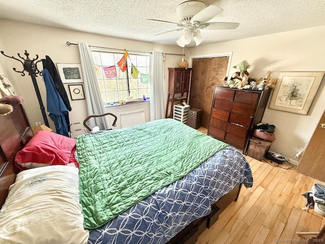 bedroom featuring ceiling fan, a textured ceiling, and wood finished floors