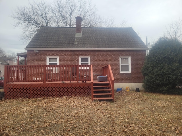 rear view of house with a wooden deck, a chimney, a shingled roof, and brick siding