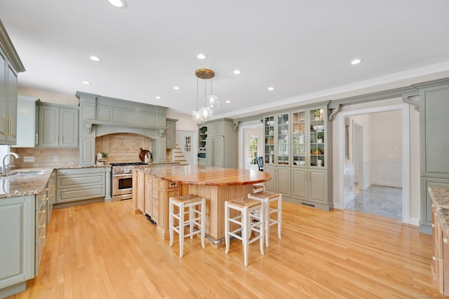 kitchen featuring tasteful backsplash, a center island, light stone countertops, high end stainless steel range oven, and a sink