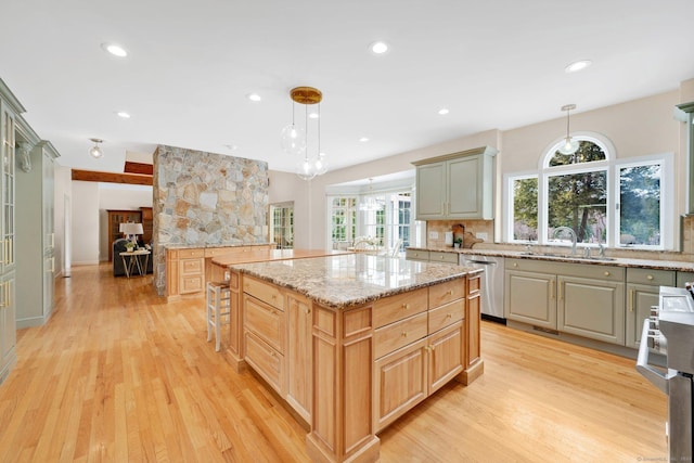 kitchen with stainless steel dishwasher, light wood-style floors, backsplash, and a healthy amount of sunlight