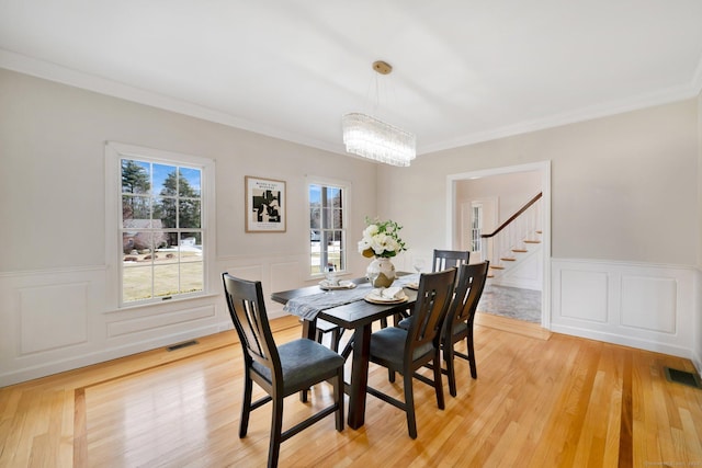 dining area with visible vents, light wood finished floors, ornamental molding, and stairway