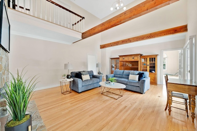 living room featuring wood finished floors, baseboards, an inviting chandelier, beam ceiling, and a high ceiling