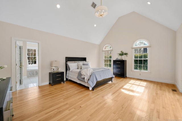 bedroom with baseboards, visible vents, light wood finished floors, and high vaulted ceiling