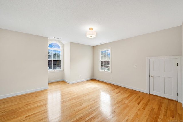 empty room featuring visible vents, baseboards, and light wood finished floors