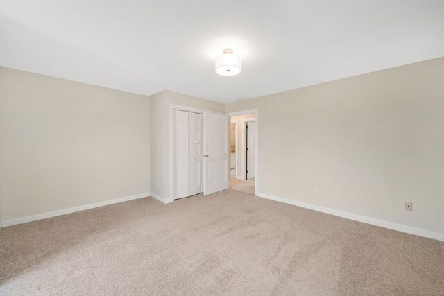 spare room with baseboards and light carpet