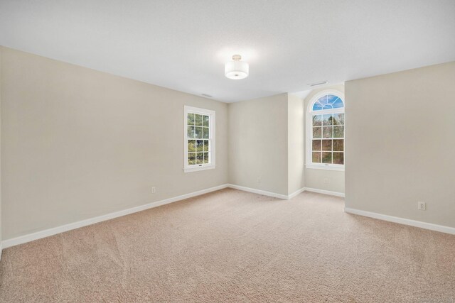 spare room featuring light carpet and baseboards