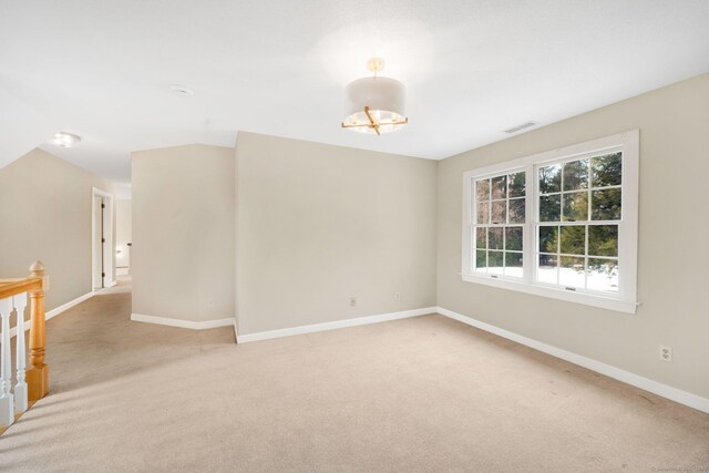 spare room featuring light carpet, visible vents, and baseboards