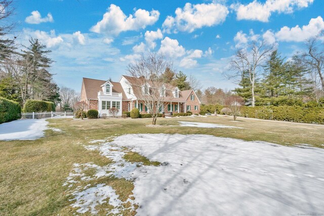 view of front of property featuring brick siding, a front yard, and fence