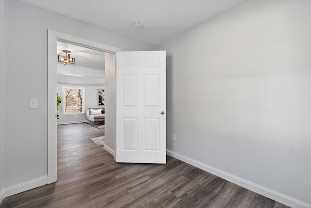 spare room featuring dark wood finished floors and baseboards