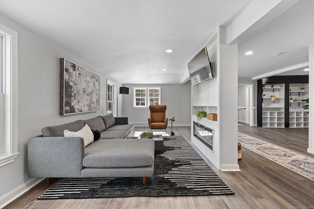 living area with recessed lighting, baseboards, wood finished floors, and a glass covered fireplace