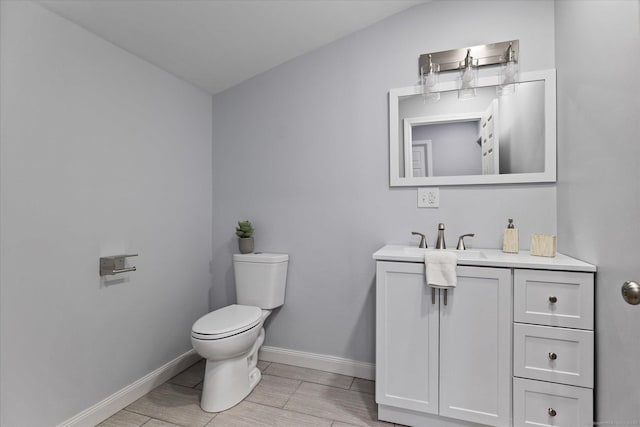 bathroom with toilet, baseboards, wood finish floors, and vanity