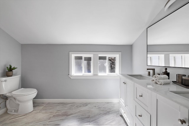 bathroom with toilet, a sink, baseboards, marble finish floor, and double vanity