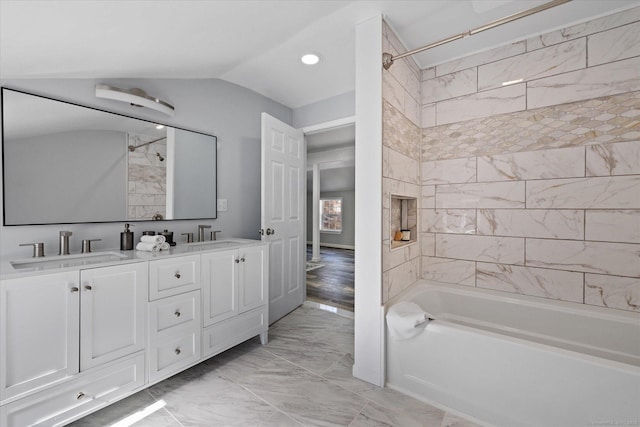 bathroom featuring vaulted ceiling, marble finish floor, double vanity, and a sink