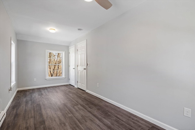 spare room featuring ceiling fan, dark wood-type flooring, and baseboards