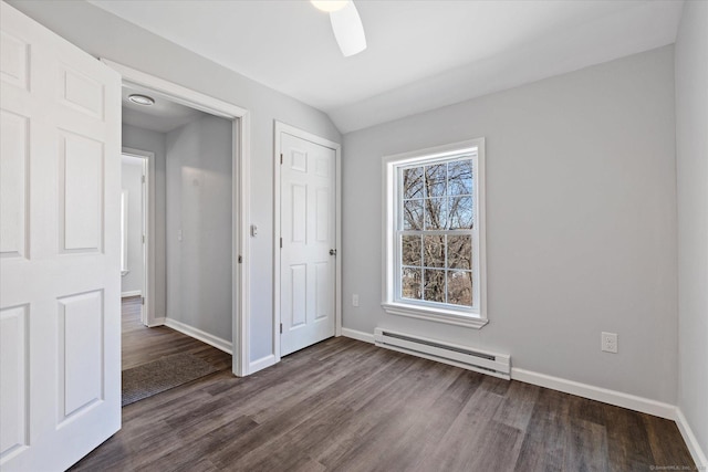 unfurnished bedroom with dark wood-style flooring, lofted ceiling, a closet, baseboard heating, and baseboards