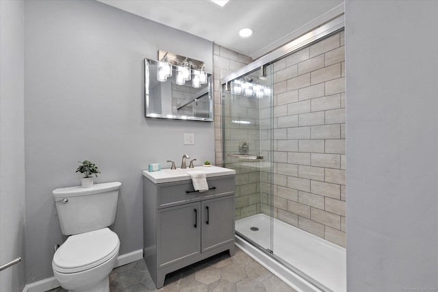 bathroom with toilet, a shower stall, baseboards, and vanity