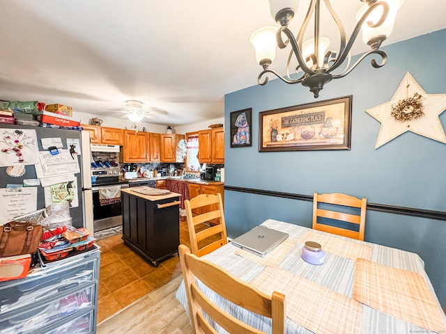 kitchen featuring a center island, light countertops, appliances with stainless steel finishes, brown cabinetry, and ceiling fan with notable chandelier