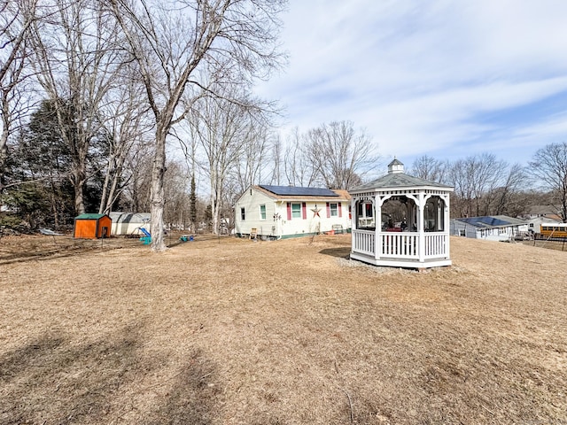 back of house with an outbuilding, a yard, solar panels, a gazebo, and a shed